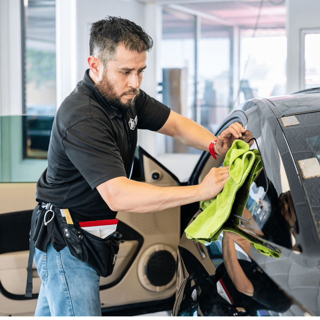 Employee wiping a window after tinting the window