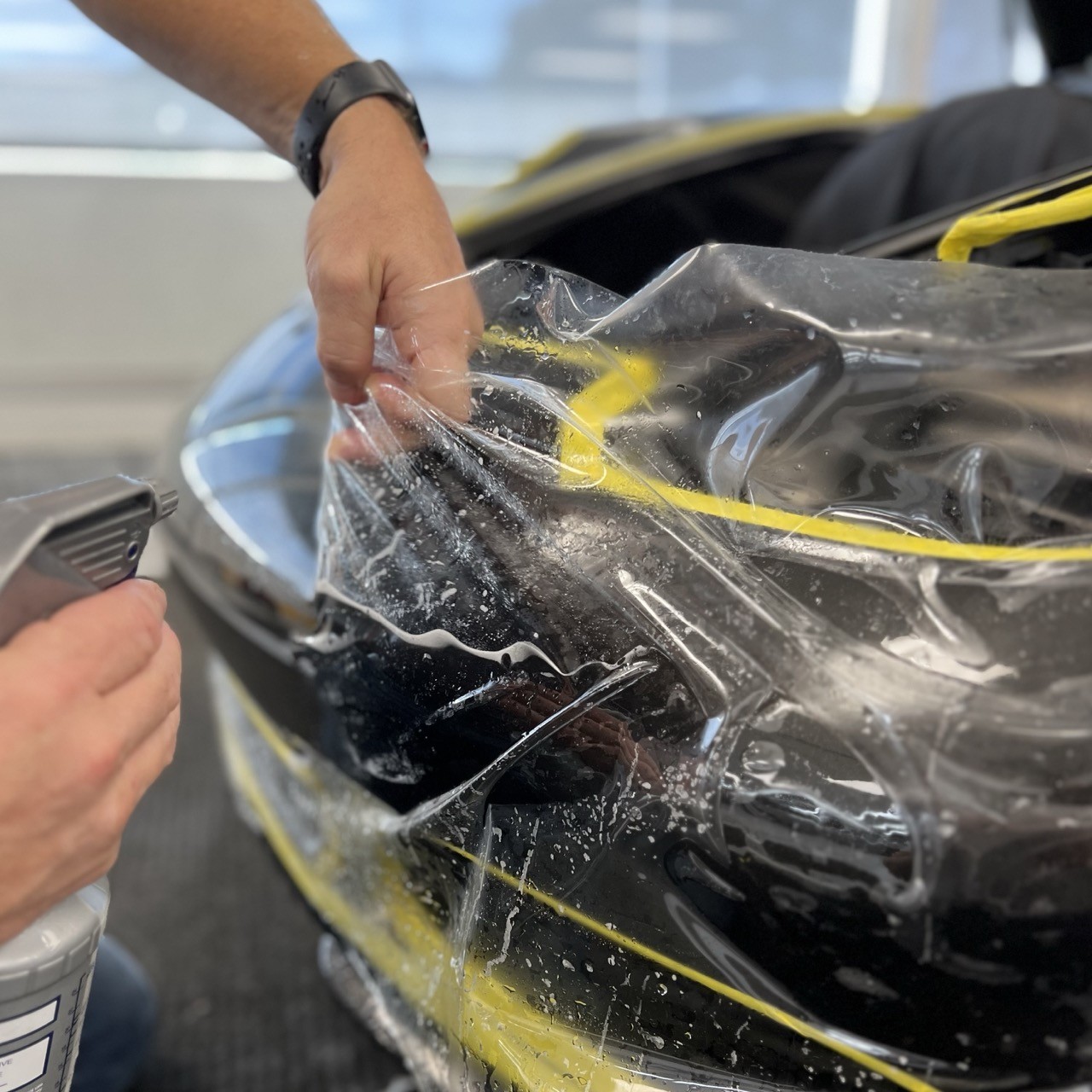 Man installing paint protection film onto vehicle